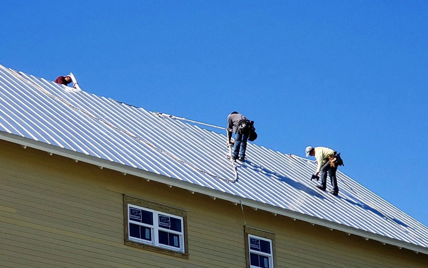A 214 Roofing crew installing clean high-performance fasteners to complete a metal roof restoration project