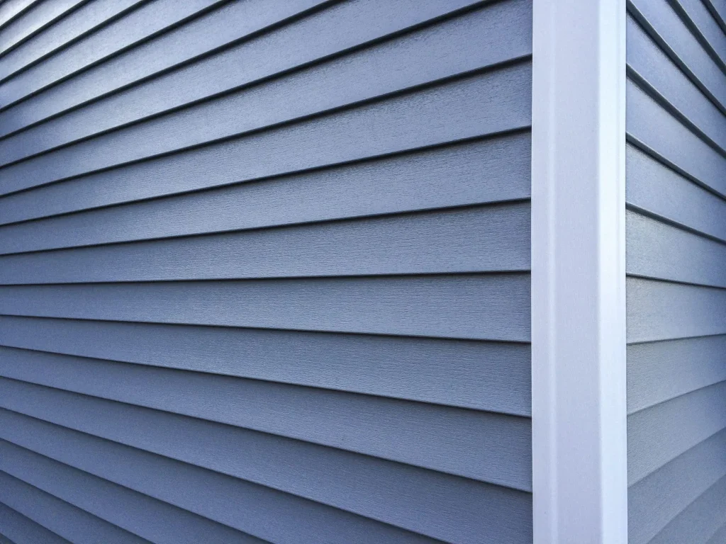 Close-up view of blue insulated vinyl siding panels and white corner post trim built for high-performance thermal insulation